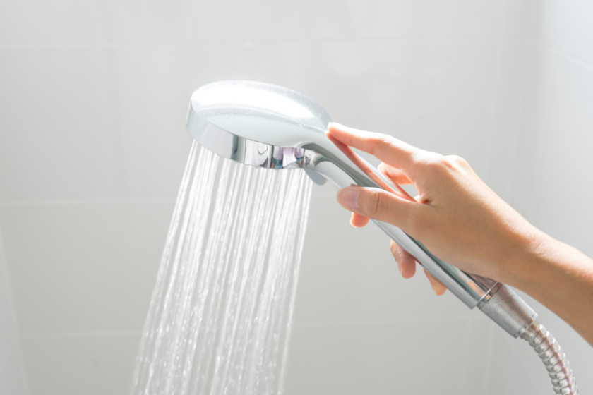 a person holding a shower head with water coming out of it
