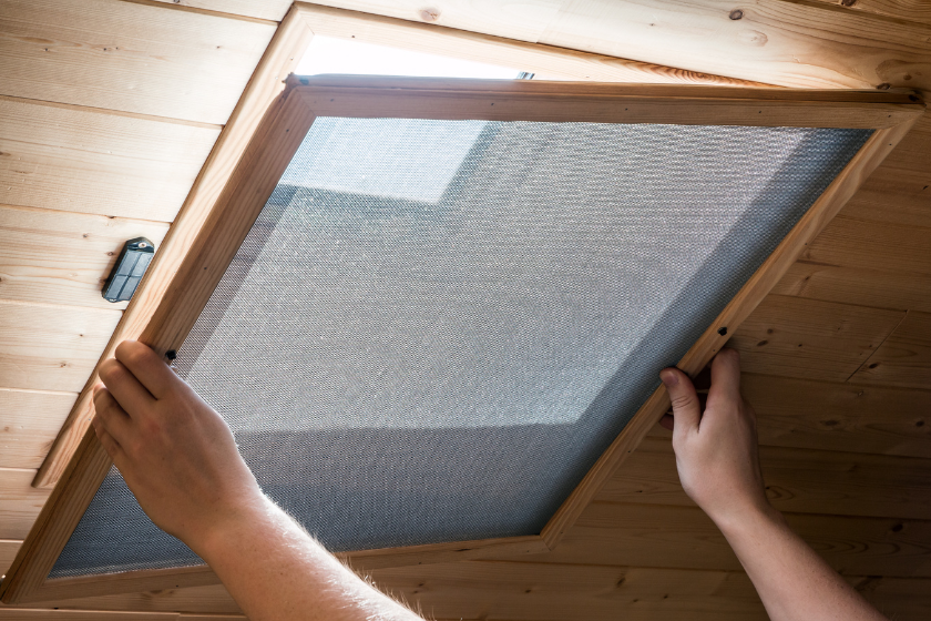 a person putting a window shade on a wooden ceiling
