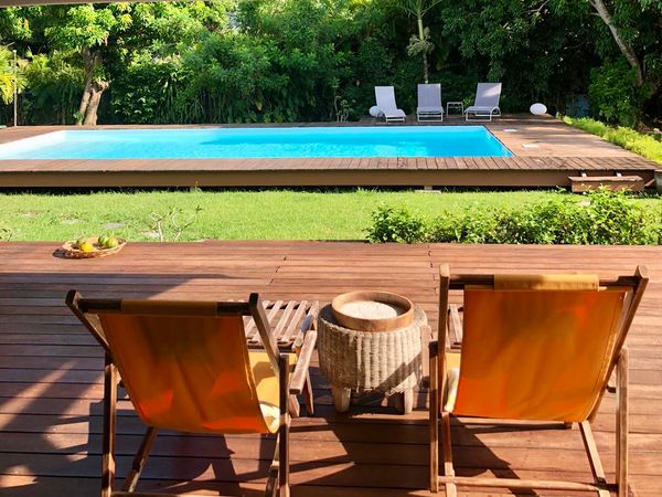 Maison spacieuse et pleine de charme au milieu d'un jardin tropical avec une grande piscine.