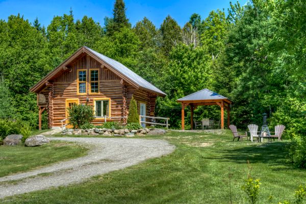 Le Chalet du Randonneur est un chalet en bois rond entouré de montagnes, parfait pour la randonnée.