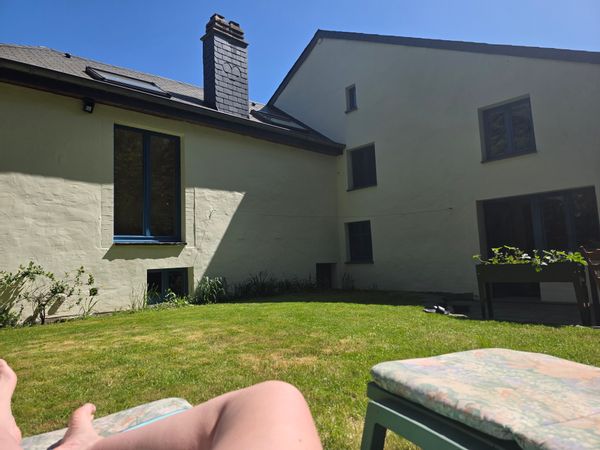 Ma maison au bout du monde avec un banc et jardin devant et un jardin derrière des transats et table