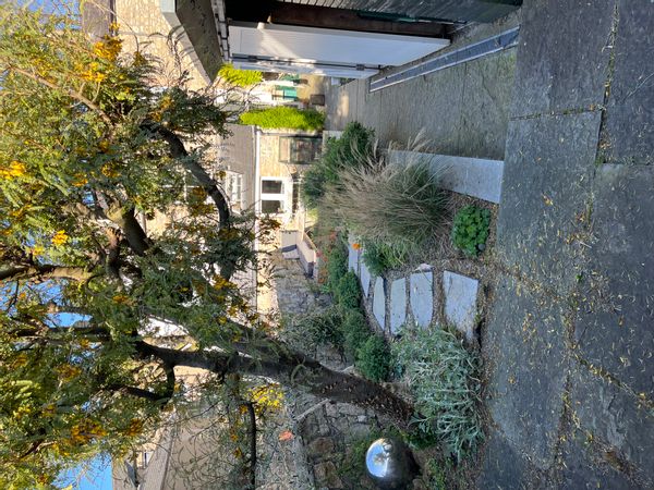 Petite maison au fond du jardin d'une plus grande maison avec accès sur la rue.