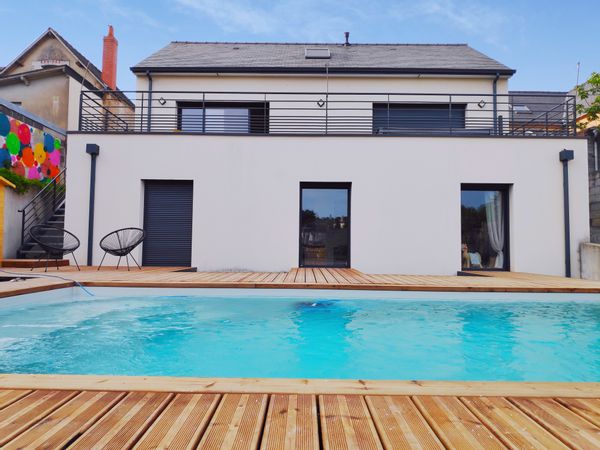 Maison contemporaine au bord de la rivière avec terrasses et piscine.