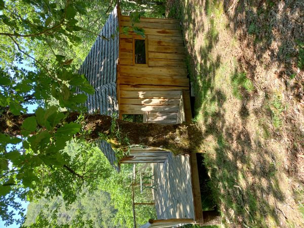 Cabane-chambre  sur pilotis avec terrasse à l'orée d'un bois, dominant la vallée du Lot.